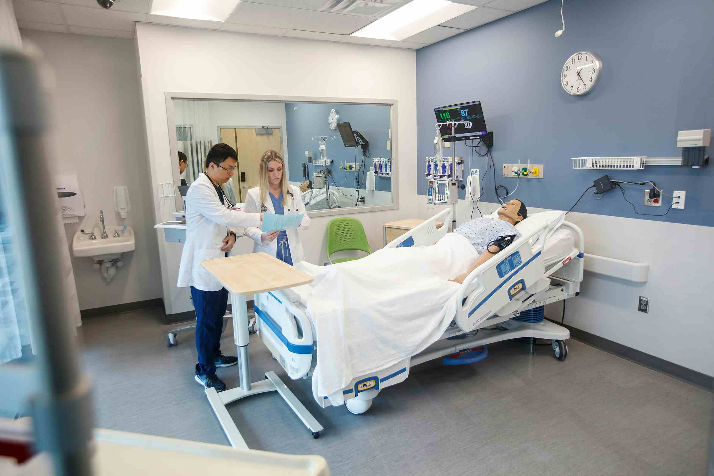 Two nursing students in the simulation room looking over a patient chart