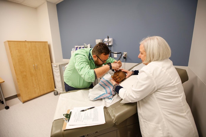 Nurse practitioner student practicing a well-child checkup using stethoscope.