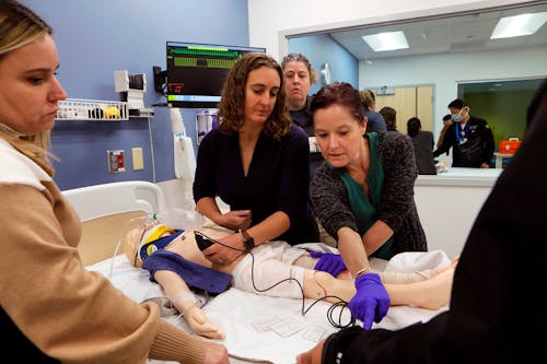 Group of instructors showing students how to work on simulation mannequins