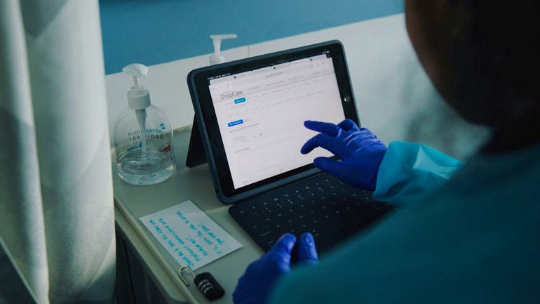 Nursing student using iPad, up-close of gloved hand