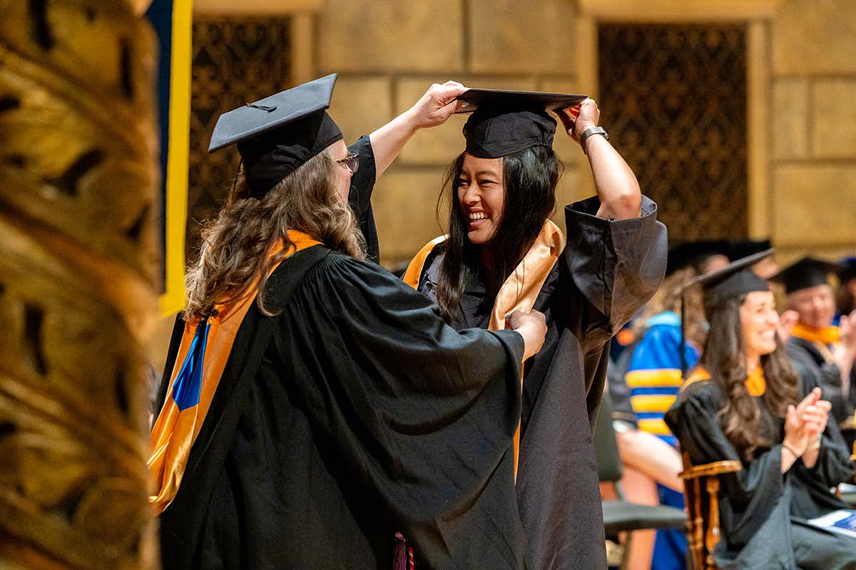 Student receiving a graduation sash from a professor during University of Rochester School of Nursing Graduation