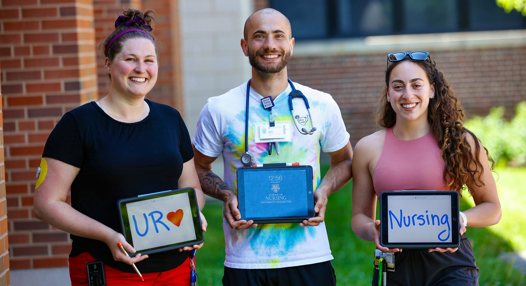 Three students holding up an iPad reading UR Nursing