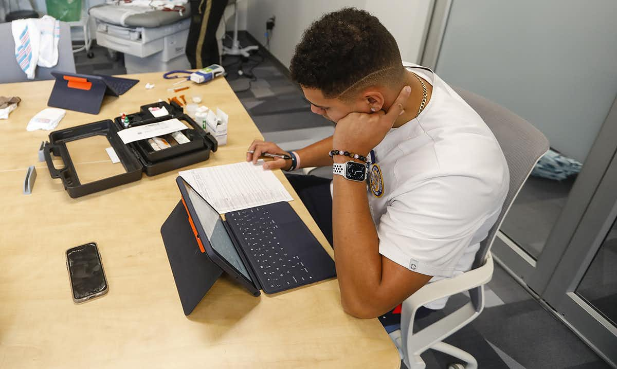 Student in a medical training room reviewing information on an iPad