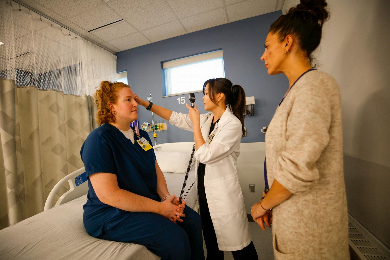 Two NP students practicing in skills lab with a faculty instructor