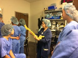 Nan Meyer, an OR nurse with nearly 30 years of experience, uses a model spine for demonstration purposes while students prepare to observe a real spine surgery.