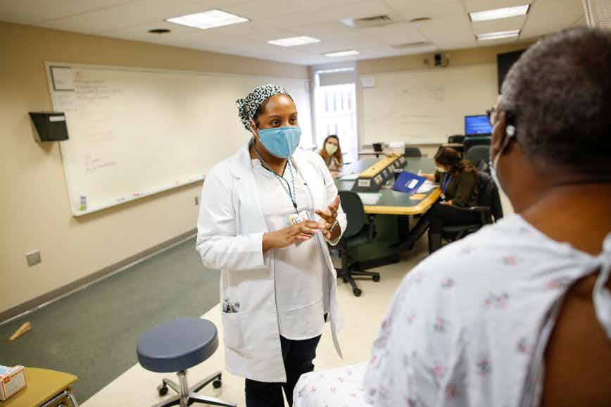 Nurse practitioner student Mary Starks talks with a standardized patient during an OSCE (objective structured clinical examination), while her instructors look on.