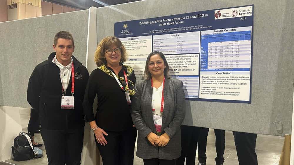 Dillon Dzikowicz, Mary Carey and Sunita Pokhrel Bhattarai stand in front of a research poster at the AHA conference.