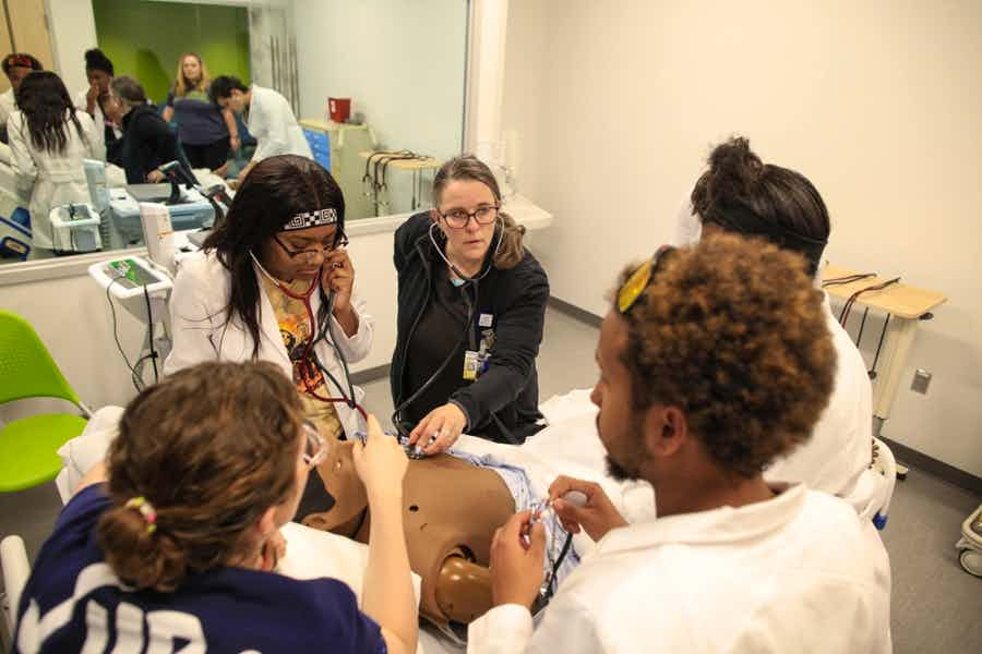 Assistant Professor Dee Dee Rutigliano leads an exercise with East High scholars in one of the School of Nursing's simulation suites.