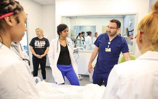 East High student Martha Beltran listens to pediatric nurse practitioner Andrew Udkovich during a lesson in the School of Nursing skills lab.