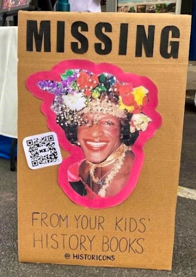 This poster was seen during the New York City Pride events this past June. It features an image of the Black transgender icon, Marsha P. Johnson, wearing a crown of flowers and smiling. Above her portrait are bold letters that say, “MISSING”, and underneath her image, the caption says, “From your kids’ history books.” The link listed on the bottom is for @historicons, a site that features historical games for children.