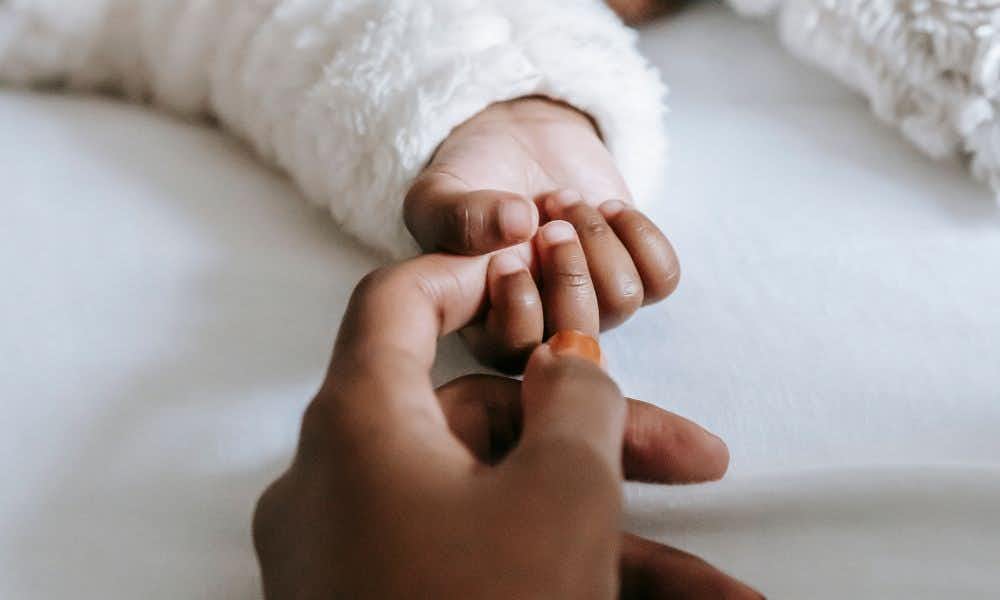 Close up of a Black woman's hand holding her baby's hand