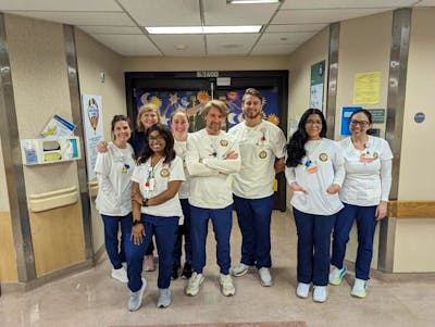 A group photo of bachelor's students in clinicals, wearing white and navy blue scrubs.