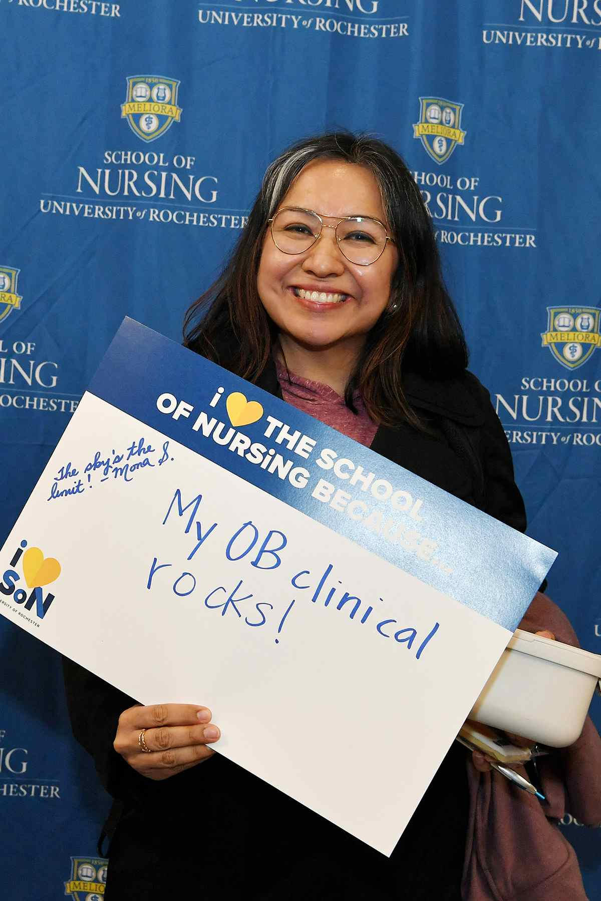 Mona Sepulveda, a UR Nursing Scholar, holds a sign that says "My OB Clinical Rocks"
