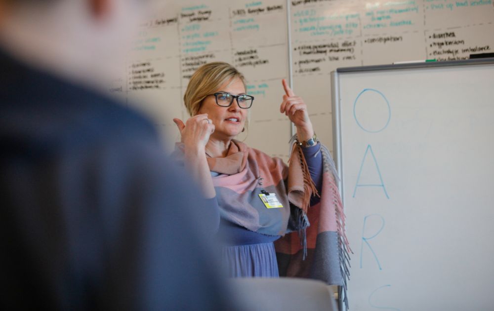 Heather Paessler-Chesterton teaches next to a whiteboard in a psychiatric NP class.