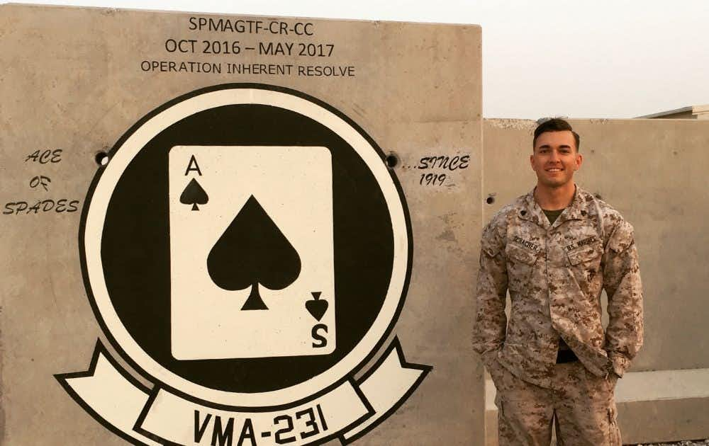 Photo of Nate Schacher with the VMA 231 Ace of Spades mural on a wall behind him.