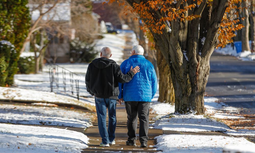 Photo shows two men walking down a snowy sidewalk.