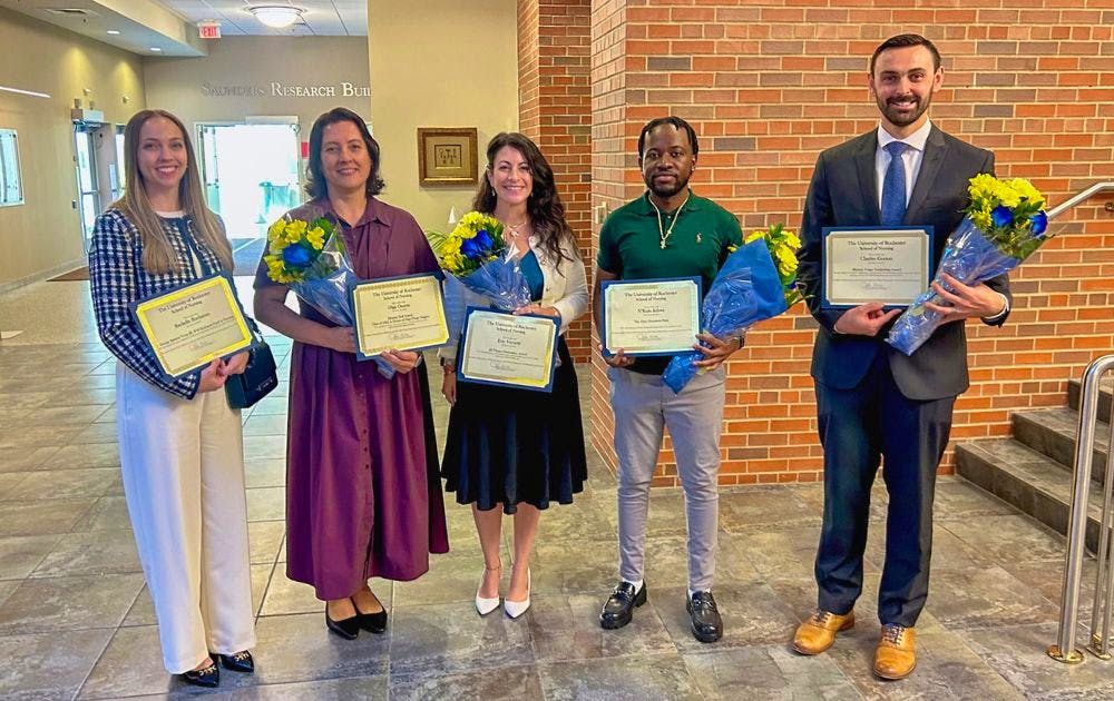 Group photo of award recipients holding flowers and certificates.