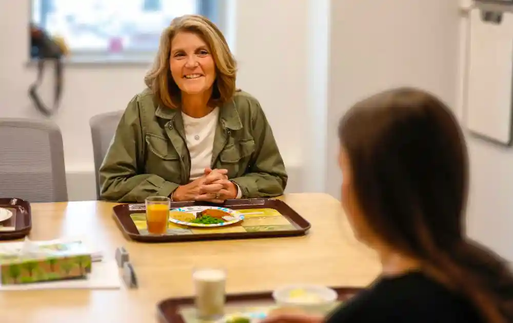 Over-the-shoulder photo of a parent peer mentor talking to a standardized patient over a meal.
