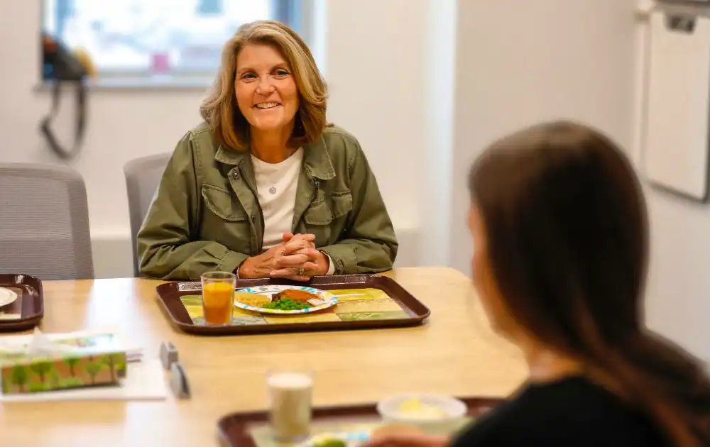 Over-the-shoulder photo of a parent peer mentor talking to a standardized patient over a meal.