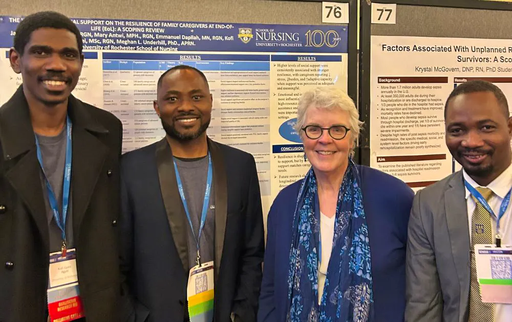 Group photo of four researchers in front of a poster presentation