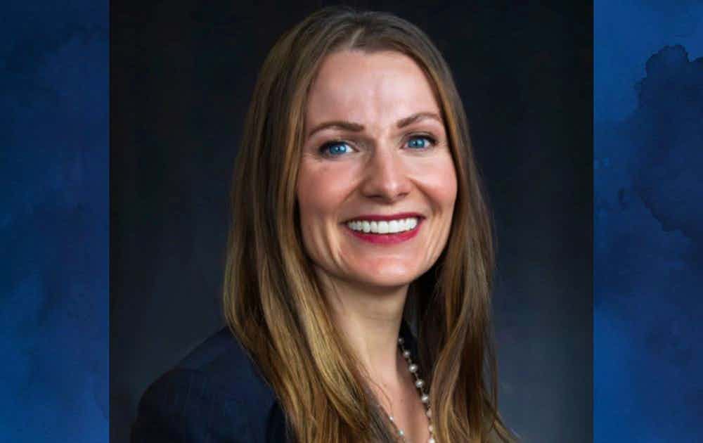 Meghan Aldrich's headshot over a blue watercolor background