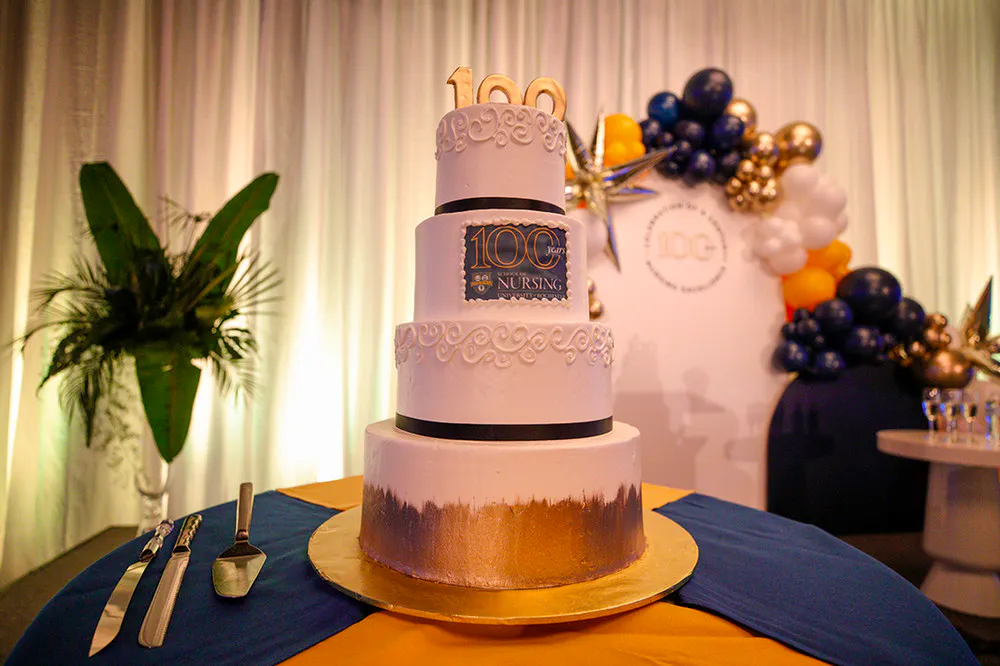 Centennial celebration four-layer cake decorated with the number 100 and UR School of Nursing logo