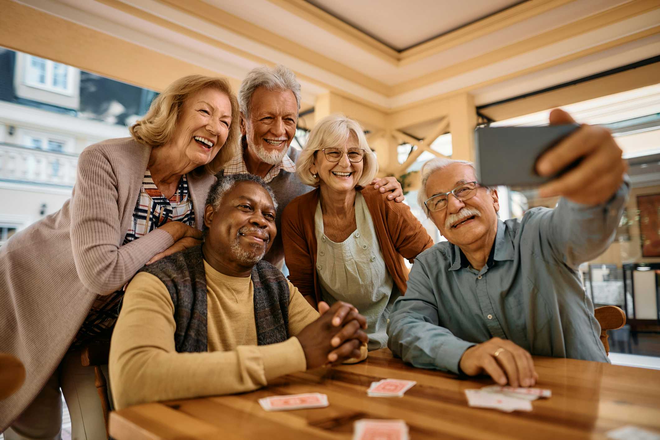 Group of older adults sitting at a table taking a selfie