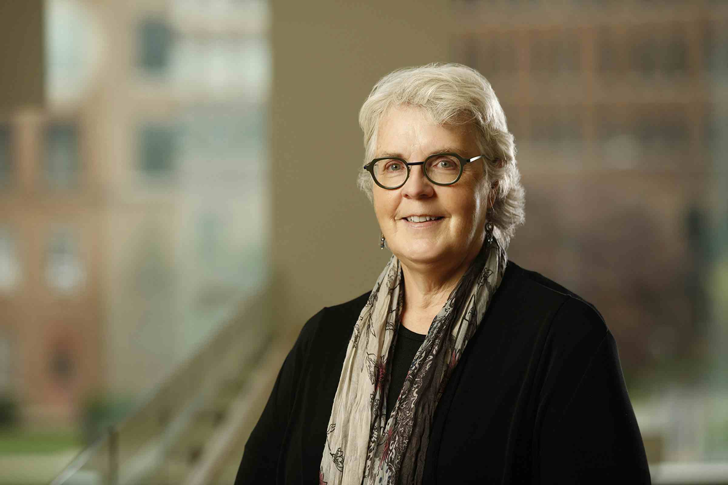 Headshot of Sally Norton wearing a black jacket and floral scarf