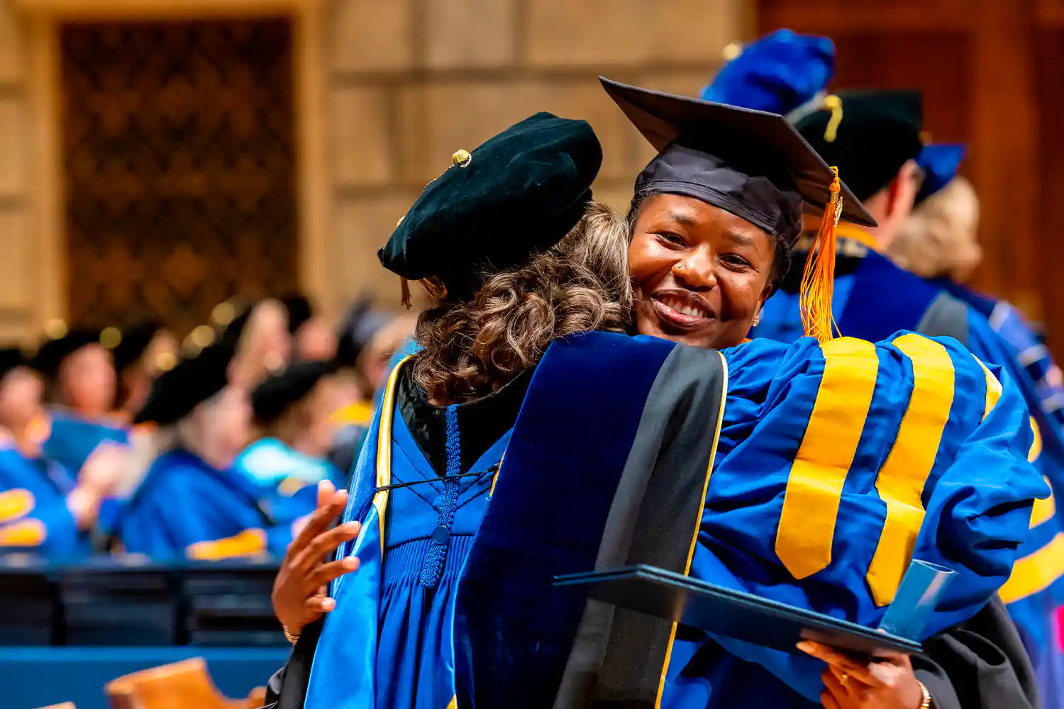 Student hugging program director during commencement
